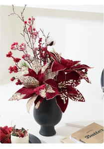 Detail of red poinsettia and berries in a matte black vase for Christmas decor