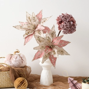 Pink Christmas flower arrangement with golden glitter edges in a white ceramic vase