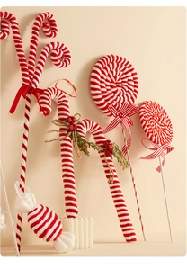 Detailed view of plush red and white candy cane ornaments with bows and pine needles