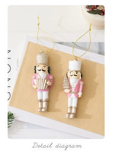 Detail of pink and gold nutcracker resin ornaments with accordion and mini tree