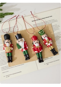 Detailed view of four resin nutcracker ornaments with festive red cords and musical themes