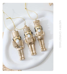 Three gold resin nutcracker soldiers Christmas tree ornaments with festive glitter accents