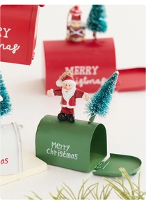 Close-up of mini iron Christmas mailboxes with Santa figurines and trees on white base