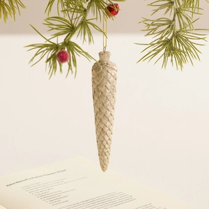 Χρυσό γκλίτερ στολίδι κουκουνάρι σαμπανιζέ κρεμασμένο σε πράσινο κλαδί χριστουγεννιάτικου δέντρου