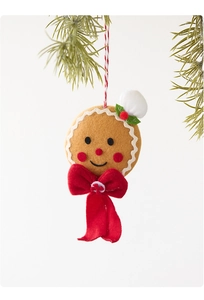Close-up of a plush gingerbread man ornament with a red bow on a green pine branch