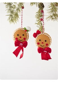 Detailed view of handmade felt gingerbread man ornaments hanging on a Christmas pine branch