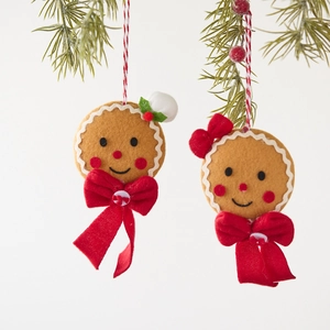 Set of two gingerbread man plush ornaments with red bows hanging on a Christmas tree