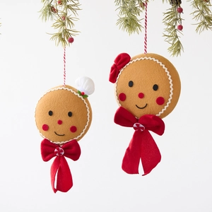 Set of two gingerbread man plush ornaments with red bows hanging on a Christmas tree