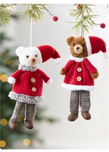 Nahaufnahme von Plüsch-Weihnachtsbären in roten Mänteln an Tannenzweigen aufgehängt