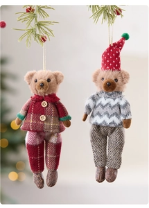 Detail of cute plush Christmas bear ornaments hanging on pine branches with warm lights