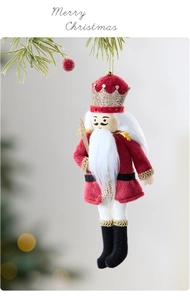 Close-up of red plush nutcracker soldier ornament hanging on a pine branch