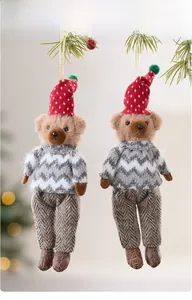 Detail of cute plush bear ornaments with red hats hanging on a festive Christmas tree branch