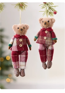 Detail of two Christmas plush bears in red plaid outfits hanging on a decorated tree