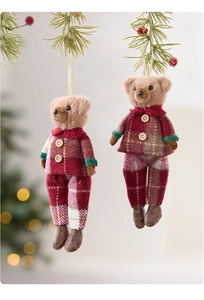 Close-up of plush Christmas bear ornaments with plaid outfits hanging on a pine branch