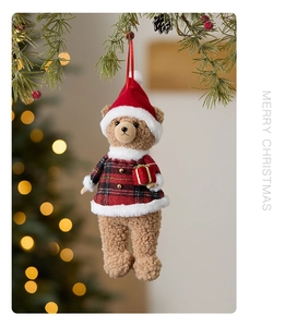 Detail of Christmas teddy bear plush ornament with red plaid sweater on pine branch