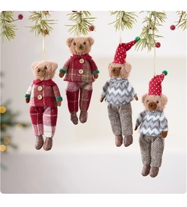 Detailed view of four plush Christmas bear ornaments hanging on festive pine branches