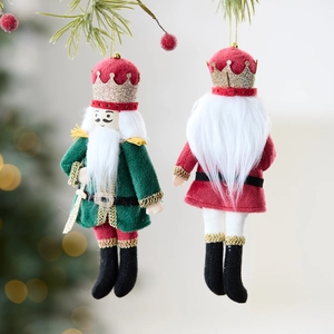 Nutcracker plush ornaments in red and green velvet hanging on a Christmas tree