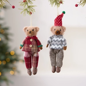 Plush Christmas bear ornaments in festive plaid and knit sweaters hanging on a tree