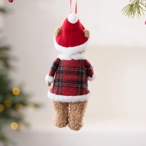 Plush Christmas teddy bear ornament in red plaid outfit hanging on festive background