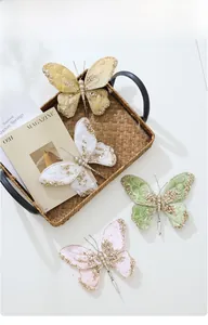Detailed view of festive butterfly clips with golden glitter finish and metal attachments