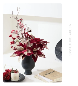 Detail of red velvet Poinsettia with gold sequins in black ceramic vase for Christmas