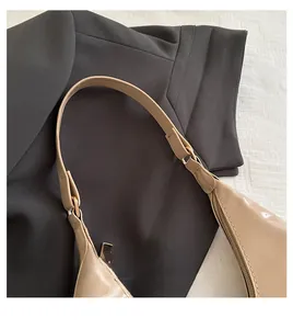 Close-up of beige patent leather shoulder bag strap stitching and gold hardware details