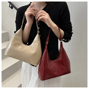 Detail van glanzende lakleren hobo-tassen in beige en bordeaux op minimalistische trap