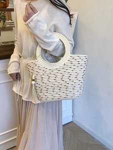 Chic cream woven straw tote bag with round handles and tassel detail for beach vacations