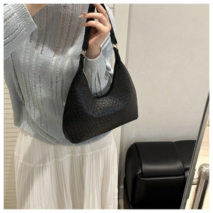Detailed close-up of a black woven leather hobo shoulder bag with textured finish