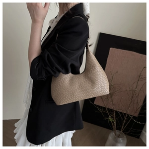 Detail of light brown woven leather hobo bag with textured pattern on female model