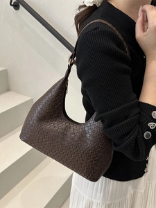 Brown woven leather underarm bag for women worn by model on minimalist background