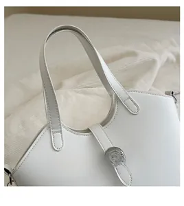 Close-up of white leather bucket bag with silver metal rings and precise stitching
