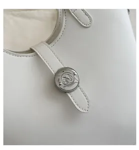 Detailed macro view of the metal N-logo twist lock on this white leather bucket bag