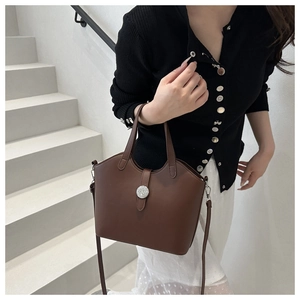Detail einer dunkelbraunen Ledertasche mit Schnalle und Schultergurt auf einer Treppe