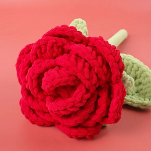 Close-up of handmade crochet red rose showing soft wool texture and layered petals