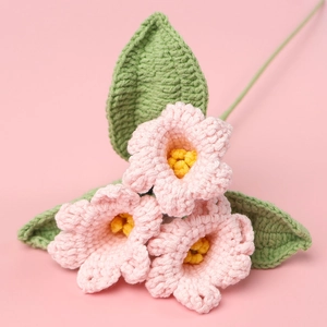 Détail de fleurs roses crochetées main avec feuilles vertes et texture d'étamines