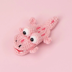 Gros plan sur une barrette crocodile en crochet rose avec yeux 3D et texture tissée