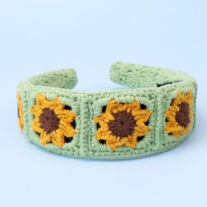 Detailed knit texture of a green headband featuring three embroidered sunflowers
