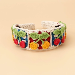 Detail of handcrafted crochet headband featuring red cherry and yellow orange motifs