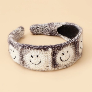 Detailed macro view of handmade knitted headband featuring black smile face patterns