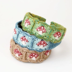 Detailed view of three handmade crochet hair clips with cute embroidered mushroom patterns