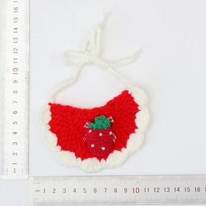 Detailed view of handmade knitted pet bib with red strawberry design and white lace border
