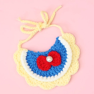 Macro shot of hand-knitted pet bib with yellow petals and red bowknot with pearl