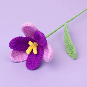 Close-up of hand-crocheted purple tulip flower with yellow stamens and green leaf
