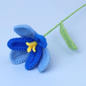 Detail of hand-crocheted gradient blue tulip with yellow stamen and green knitted stem