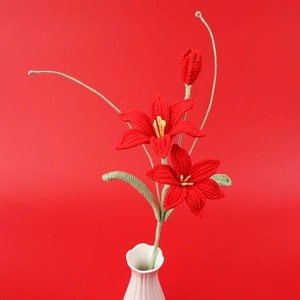 Detail of handcrafted crochet red lily flower with green leaves in a white vase
