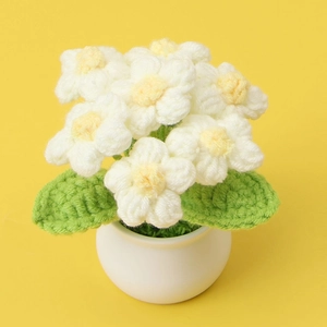 Handmade crochet white puff flower potted plant with green leaves on yellow background