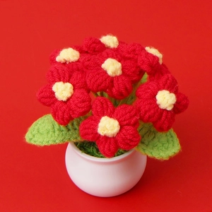 Macro shot of handmade crochet flower pot with red and yellow blossoms for home decor