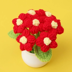 Handmade crochet red puff flower in white pot with green leaves on yellow backdrop