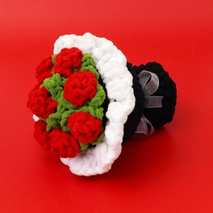 Detailed close-up of a handmade crochet bouquet with red roses and white ribbon bow